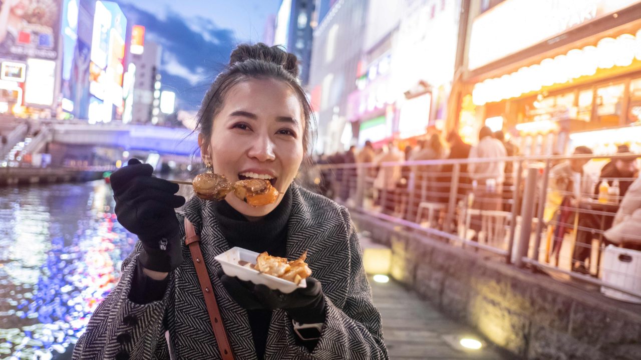 A tourist eats octopus pancakes in Osaka.