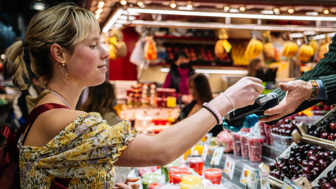 A woman pays for food using a mobile payment device at La Boqueria in Barcelona.
