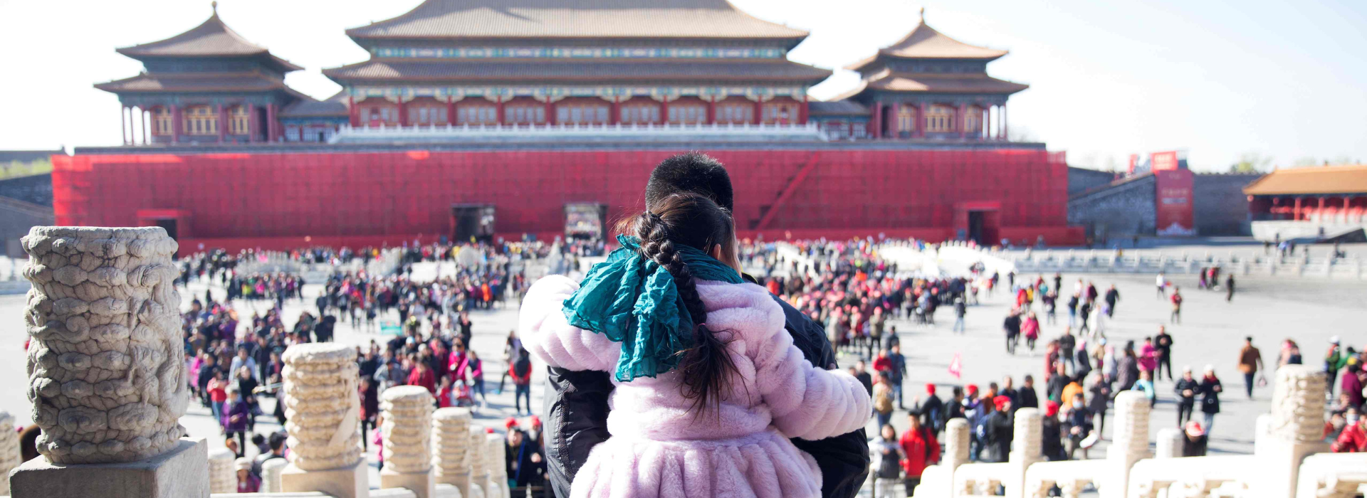 A father carrying his daughter on his back looks over the Forbidden City in Beijing.