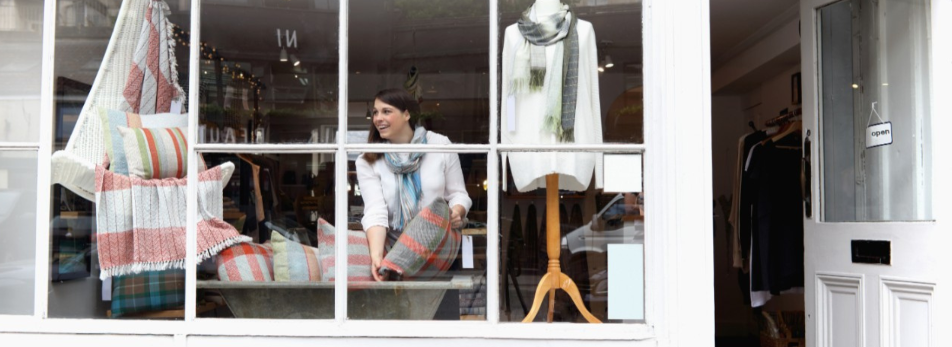 A small business owner arranges a display in a store window. 