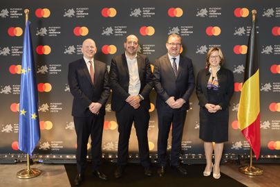 four spokespersons standing in between the European and Belgium flags, and in front of a Mastercard banner to celebrate the opening of the cyber resilience center