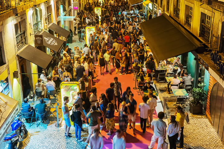 People mill around a lively street at night. 